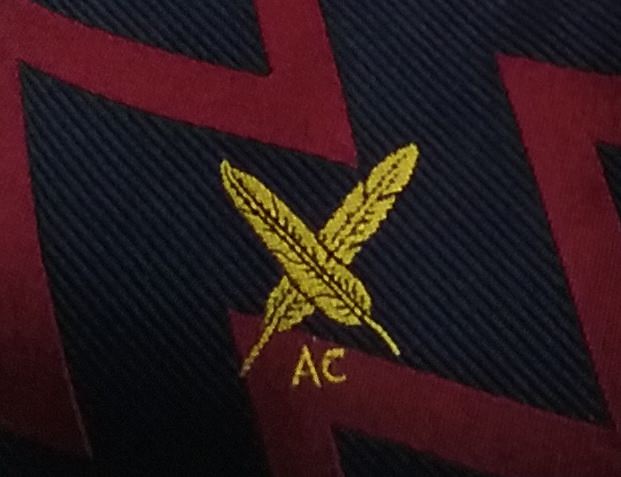 A close up image of the AC Crossed-Quills badge on an AC Tie